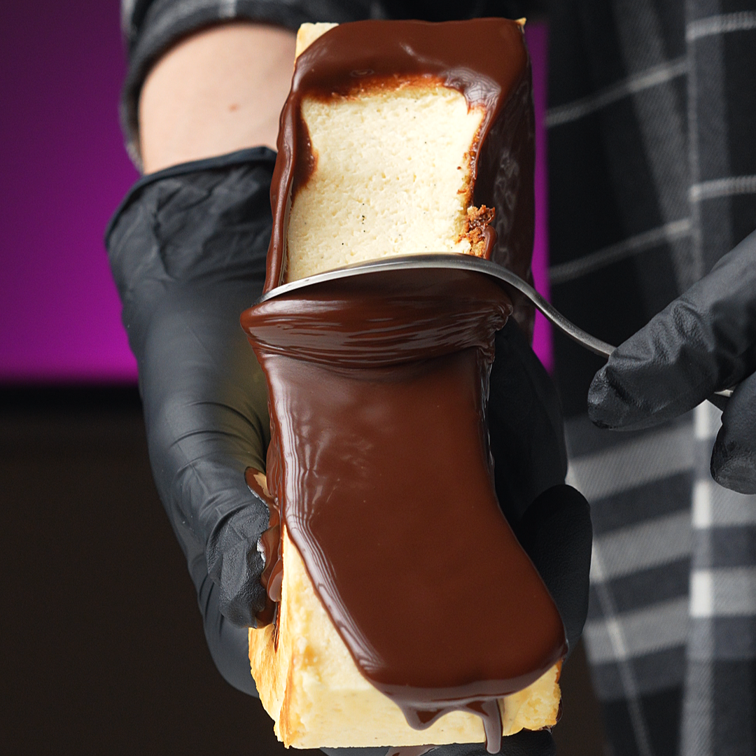 Person holding a chocolate-covered basque cheesecaked